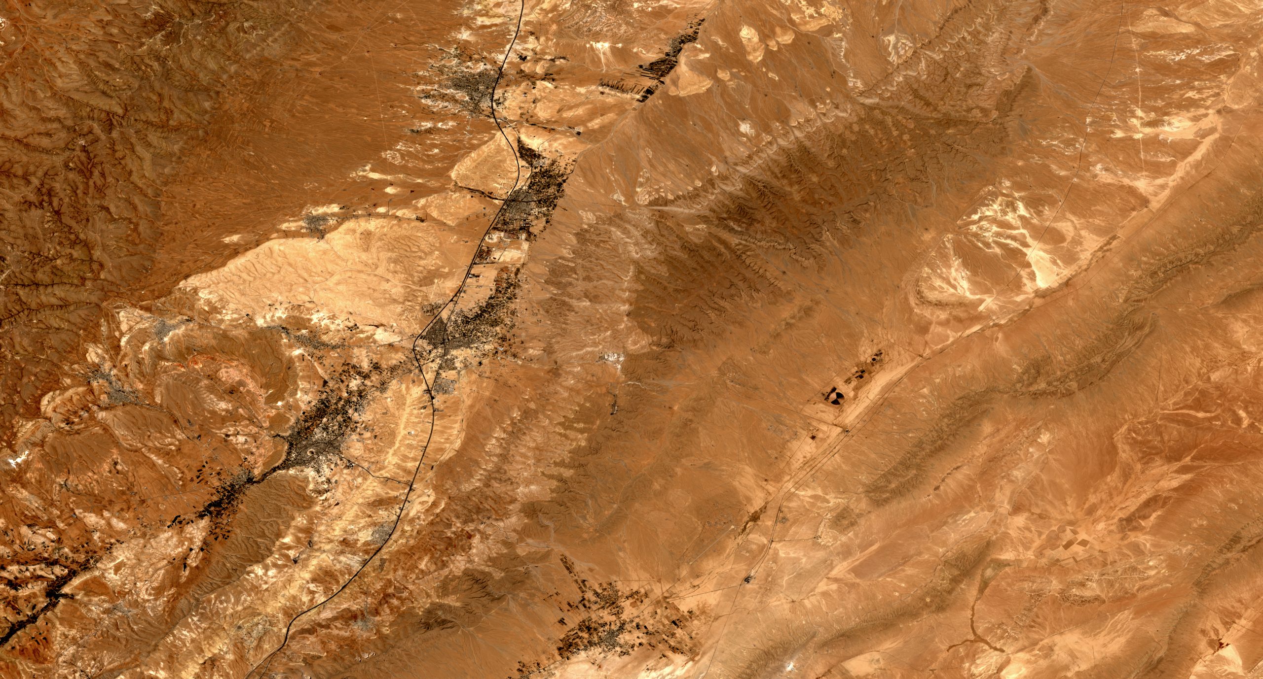 True-colour satellite image of a highland corridor with towns along a north–south route.