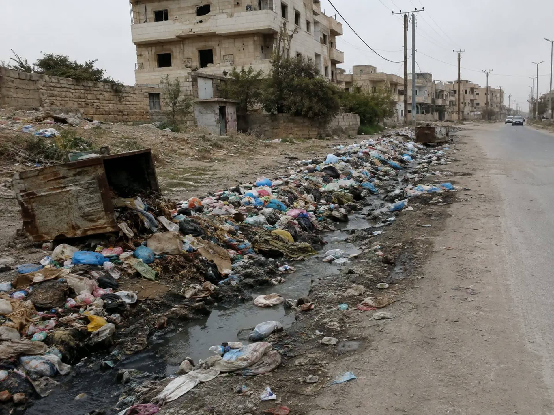Uncollected waste and polluted roadside drainage in a Syrian neighbourhood.